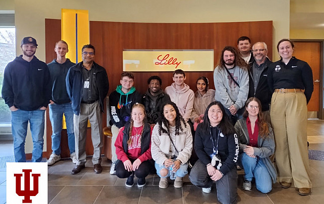 A group picture in front of a Lilly logo