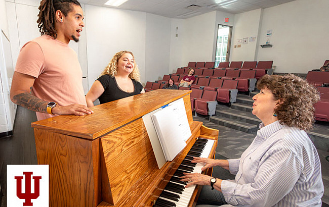 A man and two women at a piano