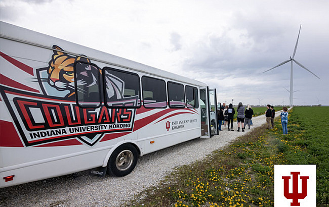 A group of people with a bus and wind turbines