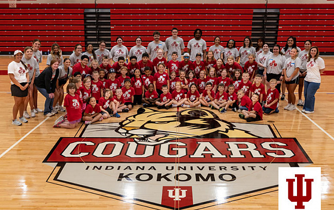 A group picture of children in red shirts and adults in gray shirts