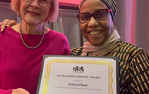 Two women smile, holding a certificate between them that says ASA Outstanding Service Award, Alwiya Omar.