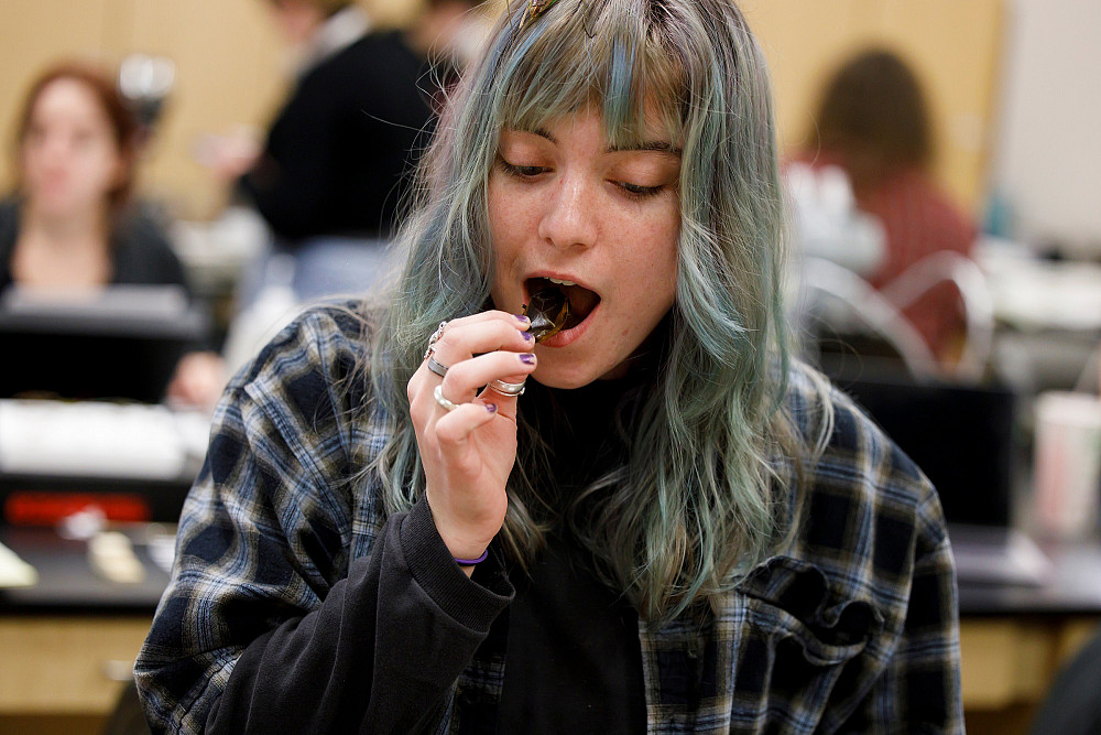 A woman puts a bug in her mouth.