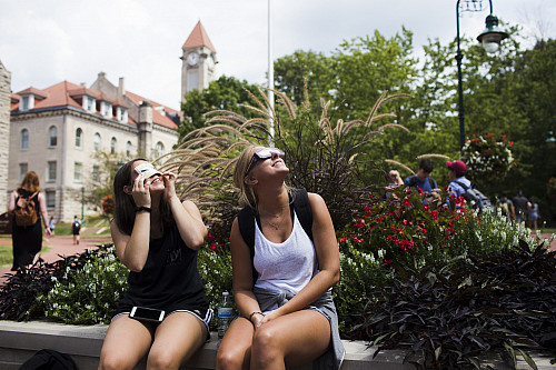 Students look up to the sky near Sample Gates
