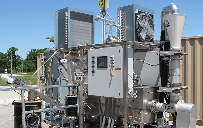 A large stainless steel machine sits in a paved outdoor area.