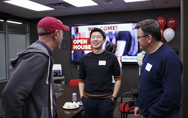 Three men talk in a conference room