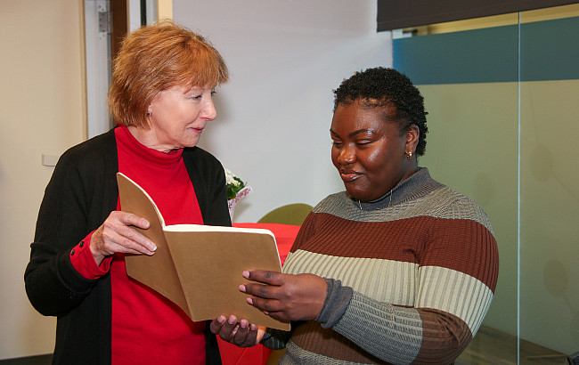 Two women holding a notebook and talking