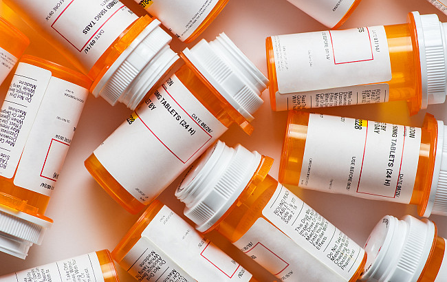 A bunch of prescription pill bottles grouped on a table with white background