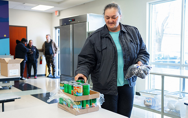A woman selects canned goods from a table