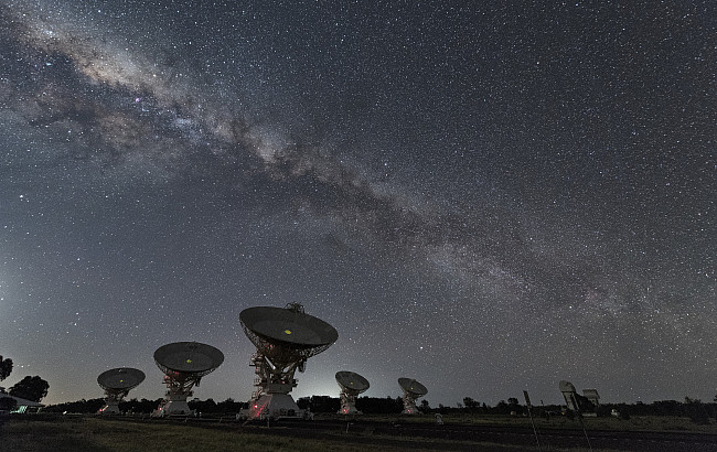 Satellites point upward in front of a starry sky