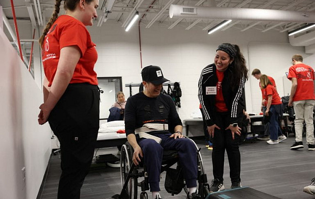 Two occupational therapists assist a wheelchair user