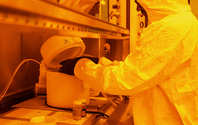 A student works in a hazmat suit in a lab