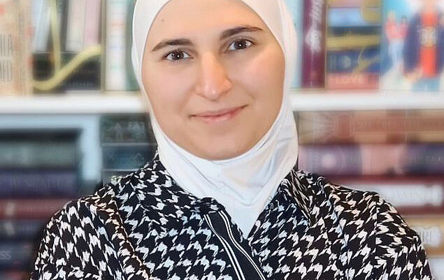 A women poses for a photo in front of a book case.