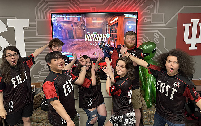 Esports team excitedly pointing at television that shows their victory