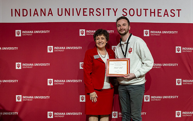 woman in red dress standing with man holding certificate