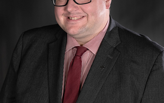 Man wearing dark suit and glasses