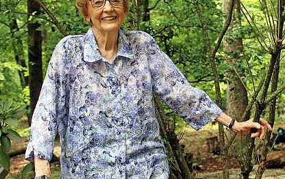 woman in floral shirt standing next to a tree