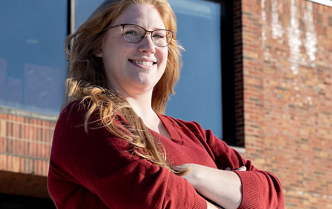 woman in red standing with arms crossed in front of a building