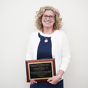 Dr. Jennifer Engel holds a plaque recognizing her leadership in the field of Education Abroad.
