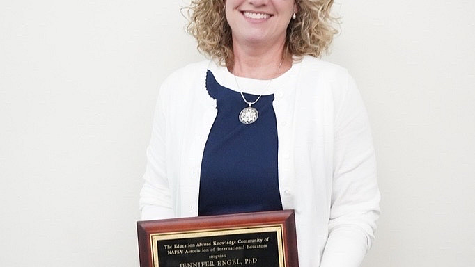 Jennifer Engel holds a plaque recognizing her leadership in the field of education abroad.