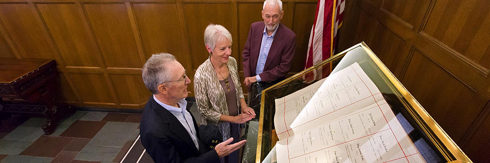 Three people view the Golden Book, IU's record of students, staff and faculty who have served in the military. Photo courtesy of Joh...