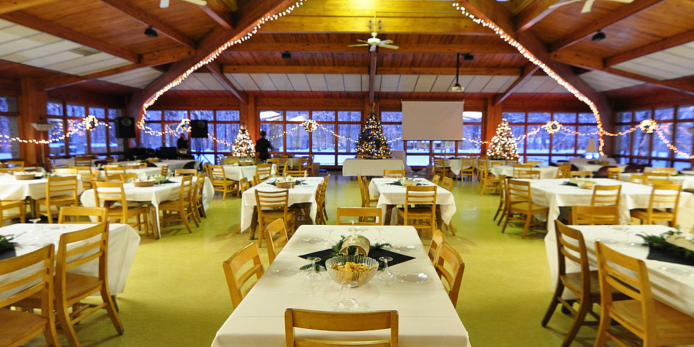 Empty tables set with white tablecloths and centerpieces in banquet room.