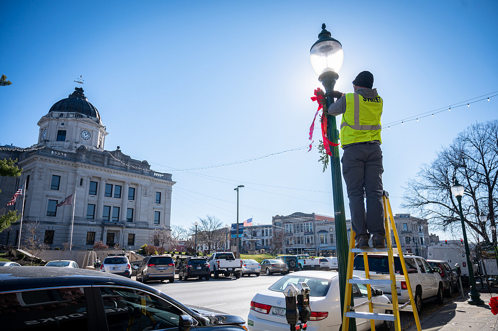 Evergreen swags are installed on street light poles around downtown Bloomington by City of Bloomington workers on Monday, Nov. 21, 2022. ...