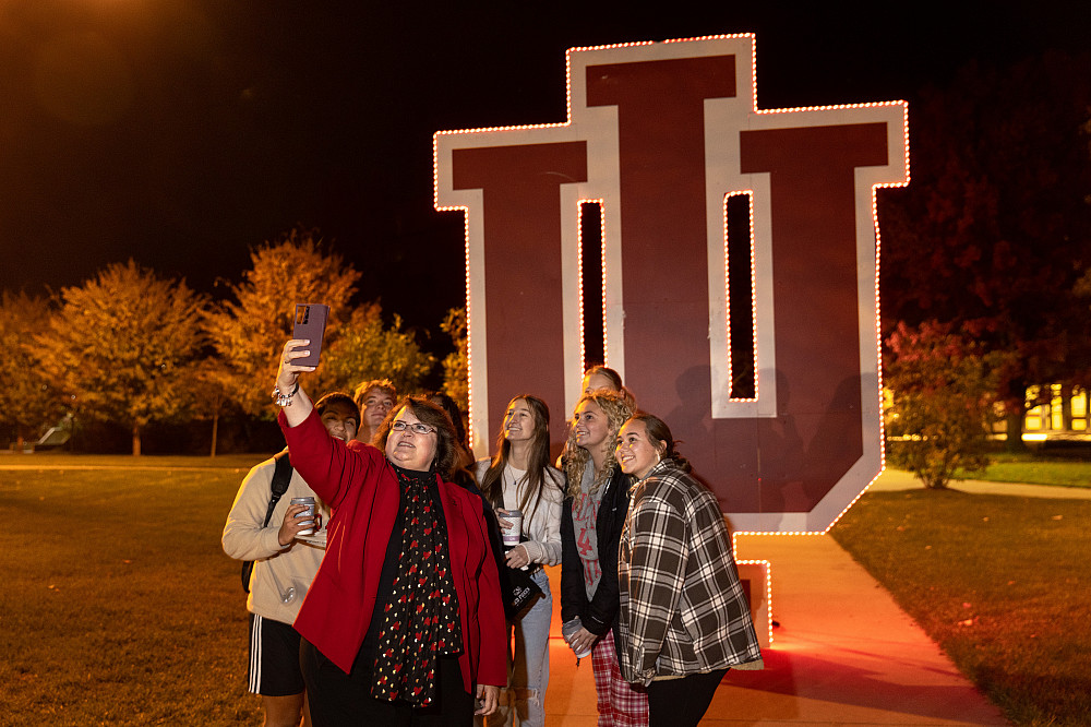 People take a selfie in front of an illuminated trident.
