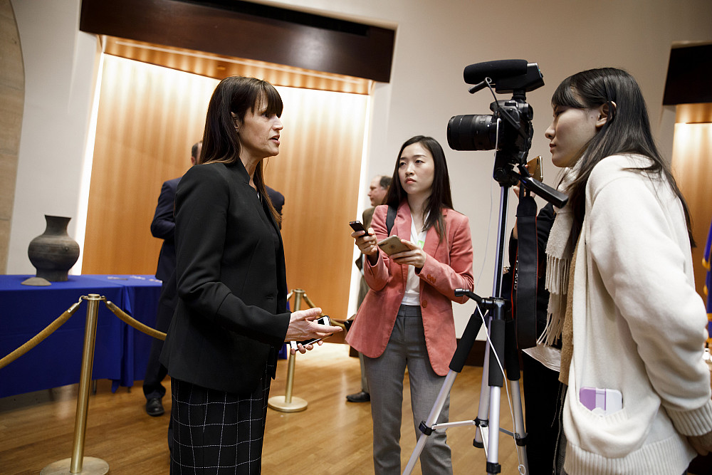 Holly Cusack-McVeigh, left, faces one reporter behind a camera and one reporter holding a small recording device.