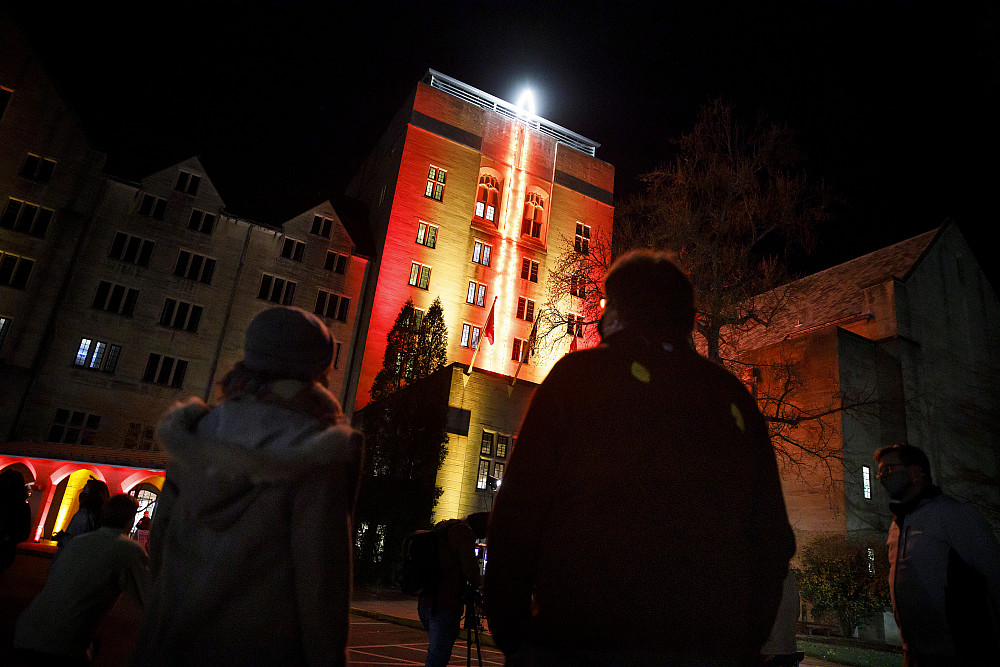 People look at holiday lights in the shape of a candle on the side of the Indiana Memorial Union Biddle Hotel and Conference Center tower.