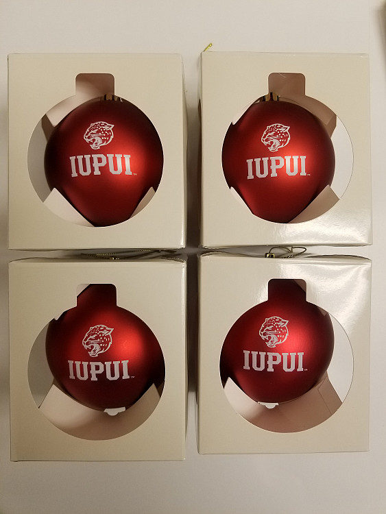 Four IUPUI Christmas ornaments in a box.