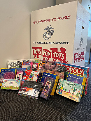 Donated toys leaning against a Toys for Tots donation bin