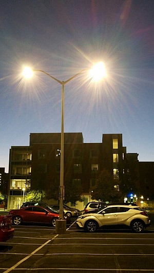 Street lights above cars parked in campus parking lot at night