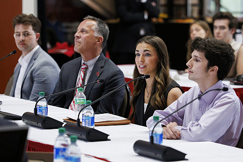 Four people sit at a table in front of microphones