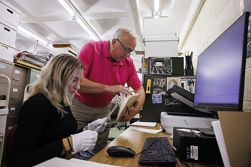 Indiana University Photograph Curator Bradley Cook searches a 1907 commencement program to help Cora Deemer, a recent graduate from Bloom...