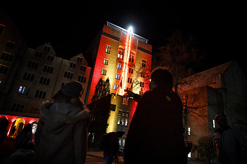 Spectators take in the holiday candle illuminating the side of the Indiana Memorial Union Biddle Hotel and Conference Center tower after ...