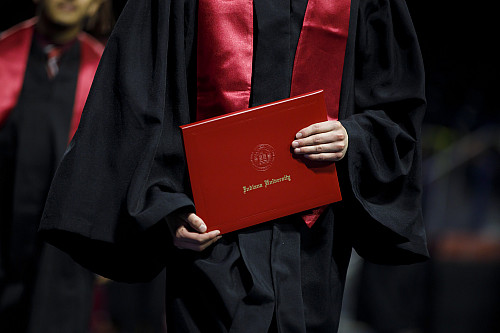 A graduate carries a diploma cover back to her seat during the Indiana University South Bend Commencement at the Joyce Center on Tuesday,...