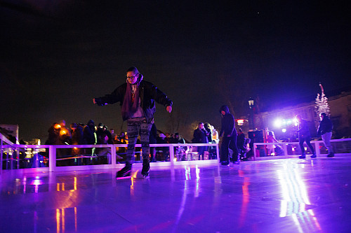 People ice skating on an outdoor rink at night.