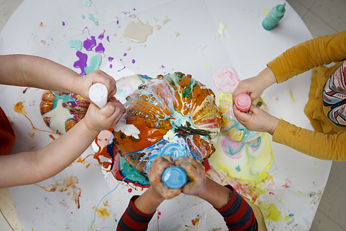 Toddlers use a combination of paint and glue to cover a set of pumpkins at the Campus View Child Care Center at IU Bloomington on Wednesd...