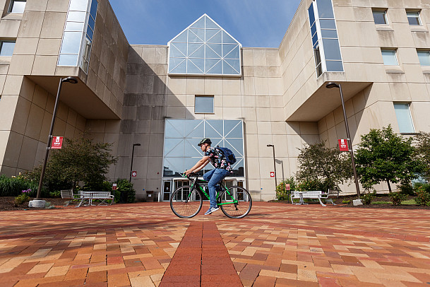 A person rides a bike in front of University Library at IUPUI. 