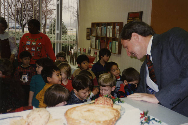 Gerald Bepko sits at a table near a crowd of children