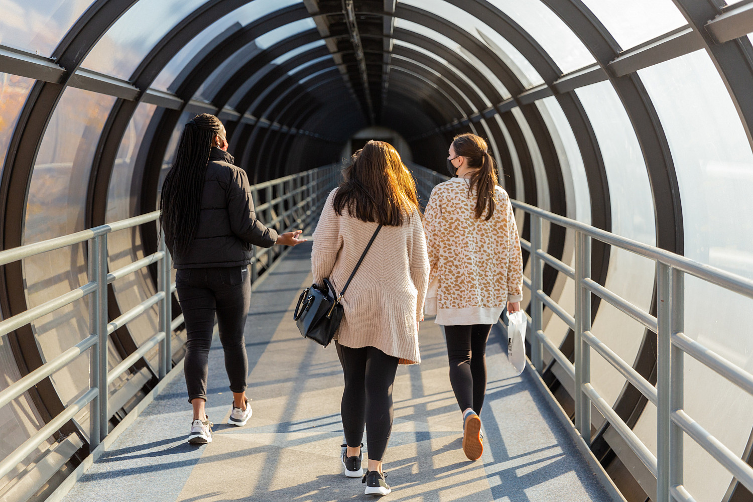 Three people walking in a covered walkway.
