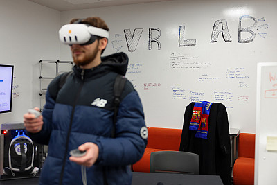 A student wearing virtual reality glasses in the VR Lab in University Library